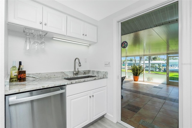 kitchen with a sink, white cabinets, light stone countertops, and stainless steel dishwasher