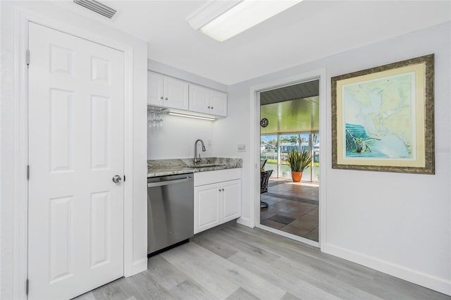 kitchen featuring dishwasher, light stone countertops, white cabinetry, and a sink