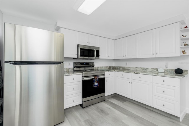 kitchen with light stone counters, white cabinetry, stainless steel appliances, and open shelves