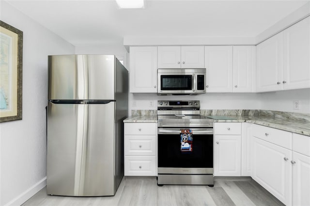 kitchen with stainless steel appliances, baseboards, white cabinets, and light wood finished floors