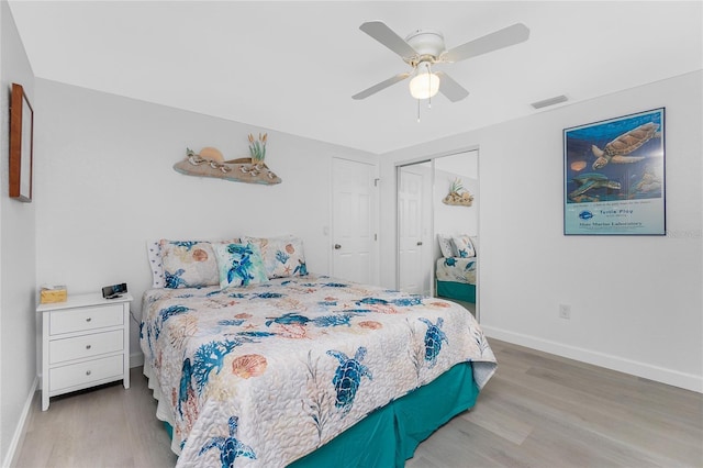 bedroom with wood finished floors, visible vents, a closet, and baseboards