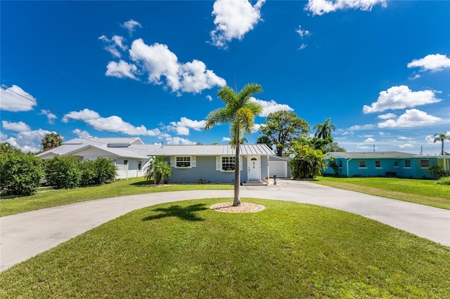 single story home featuring metal roof, curved driveway, a garage, and a front lawn