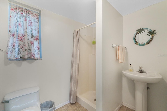 bathroom with toilet, baseboards, and a stall shower