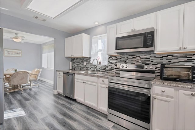 kitchen with ceiling fan, sink, white cabinetry, stainless steel appliances, and light hardwood / wood-style floors