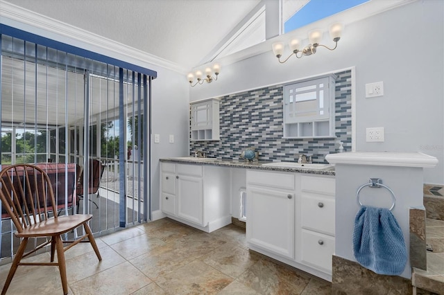 bathroom featuring vanity, ornamental molding, a textured ceiling, vaulted ceiling, and decorative backsplash