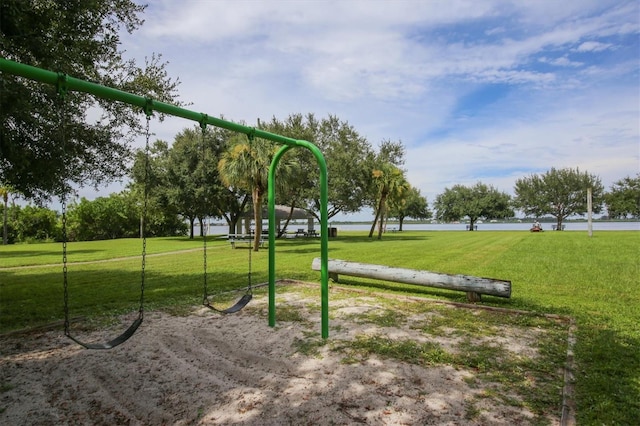 view of property's community featuring a lawn, a water view, and a playground