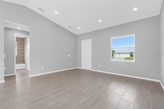 spare room featuring light wood-type flooring and lofted ceiling