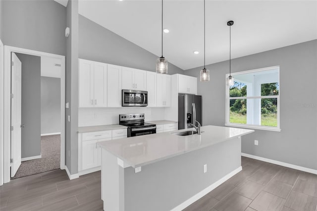 kitchen featuring pendant lighting, white cabinets, a kitchen island with sink, stainless steel appliances, and vaulted ceiling