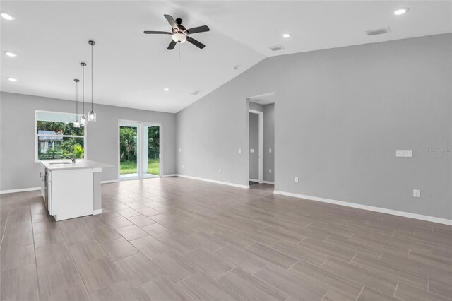 unfurnished living room featuring ceiling fan, lofted ceiling, light wood-type flooring, and sink