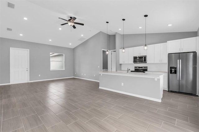 kitchen featuring hanging light fixtures, white cabinets, stainless steel appliances, ceiling fan, and a center island with sink