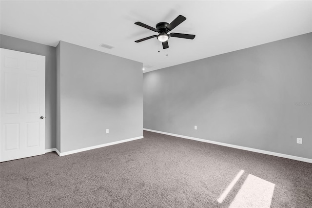 spare room featuring dark carpet and ceiling fan