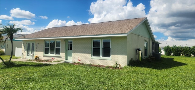 rear view of house featuring central AC unit and a lawn