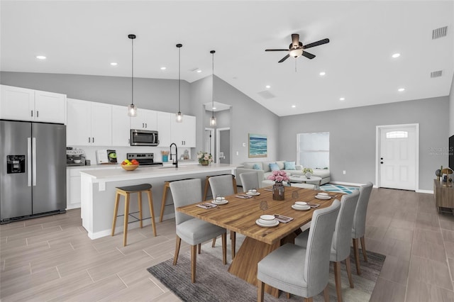 dining space with sink, light wood-type flooring, high vaulted ceiling, and ceiling fan