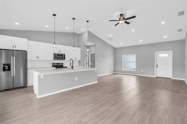 kitchen featuring an island with sink, hanging light fixtures, white cabinetry, ceiling fan, and stainless steel appliances