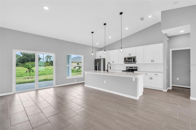 kitchen with appliances with stainless steel finishes, sink, white cabinetry, high vaulted ceiling, and a kitchen island with sink