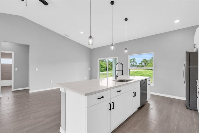 kitchen with hanging light fixtures, stainless steel appliances, a center island with sink, sink, and white cabinetry