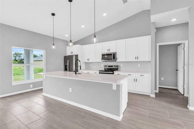 kitchen with white cabinetry, appliances with stainless steel finishes, decorative light fixtures, and a kitchen island with sink