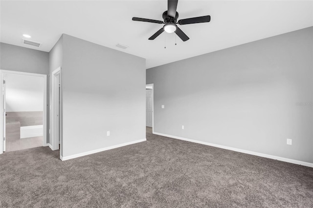 interior space with ceiling fan, ensuite bath, and dark colored carpet