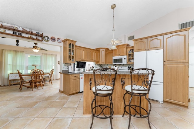 kitchen with white appliances, vaulted ceiling, a center island, and light tile patterned floors