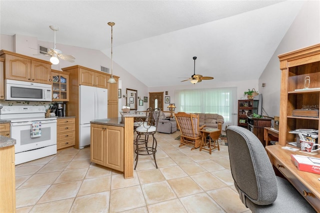 kitchen featuring a kitchen breakfast bar, white appliances, a kitchen island, light tile patterned floors, and lofted ceiling