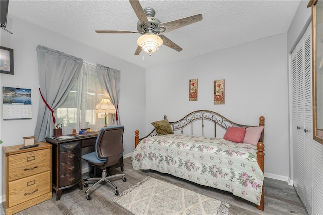 bedroom with a closet, hardwood / wood-style flooring, ceiling fan, and a textured ceiling