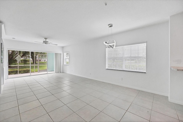 empty room featuring ceiling fan with notable chandelier and light tile patterned floors