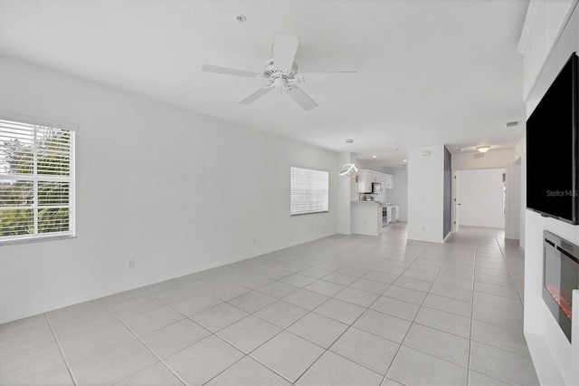 unfurnished living room featuring ceiling fan with notable chandelier and light tile patterned floors