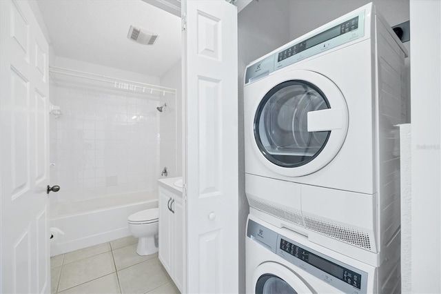 clothes washing area with stacked washing maching and dryer and light tile patterned floors