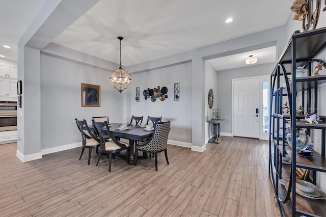 dining room with light wood-type flooring and a chandelier