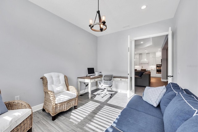 office area featuring an inviting chandelier and hardwood / wood-style flooring