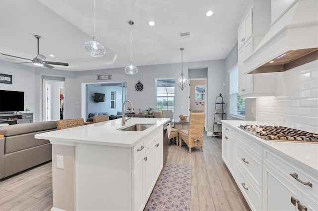 kitchen featuring hanging light fixtures, sink, a kitchen island with sink, light hardwood / wood-style flooring, and custom range hood