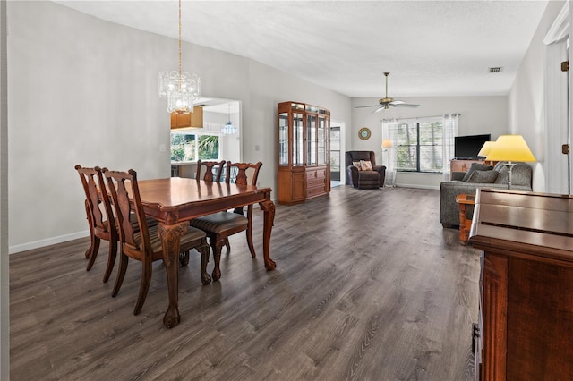 dining space with plenty of natural light, lofted ceiling, dark wood-type flooring, and ceiling fan with notable chandelier