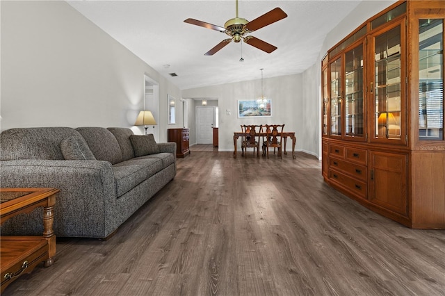 living room with ceiling fan with notable chandelier, dark hardwood / wood-style floors, and lofted ceiling