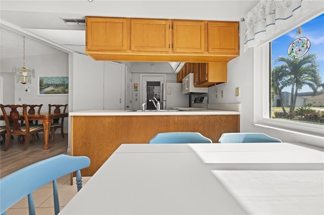 kitchen featuring light wood-type flooring, white appliances, sink, a notable chandelier, and hanging light fixtures