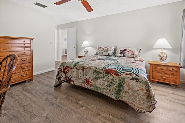 bedroom featuring wood-type flooring, a textured ceiling, and ceiling fan