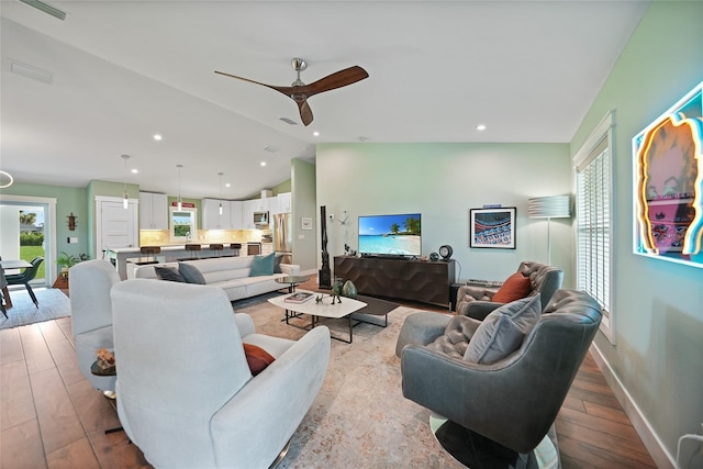 living room featuring ceiling fan, lofted ceiling, and light hardwood / wood-style floors