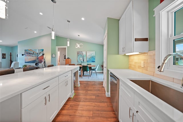 kitchen featuring white cabinets, vaulted ceiling, decorative light fixtures, and dishwasher