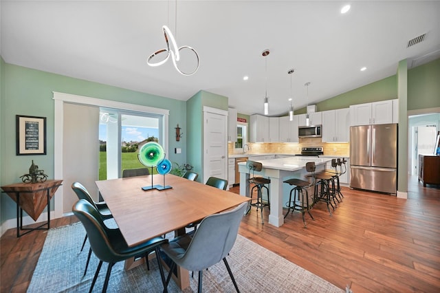 dining room with vaulted ceiling, hardwood / wood-style flooring, and sink