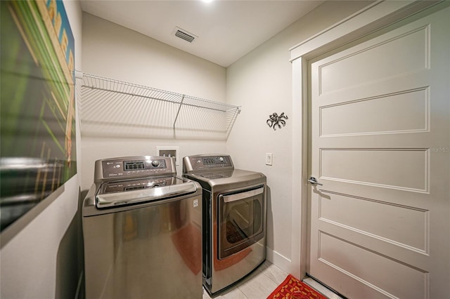 clothes washing area with washing machine and clothes dryer and light tile patterned floors