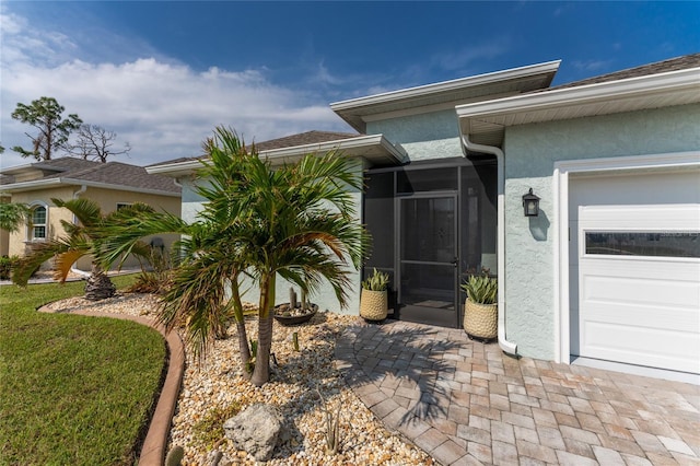 entrance to property with a garage and a lawn