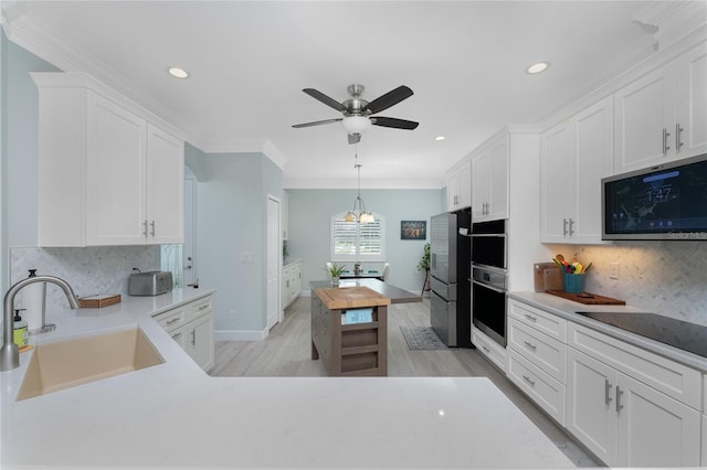 kitchen with decorative backsplash, white cabinets, stainless steel appliances, crown molding, and sink