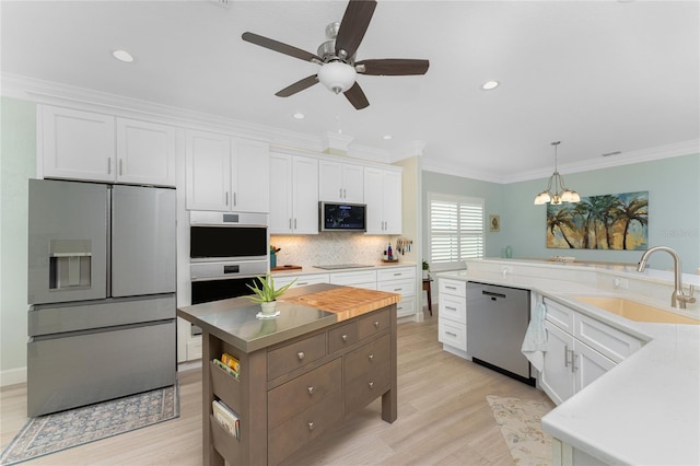 kitchen featuring sink, appliances with stainless steel finishes, decorative light fixtures, and white cabinetry