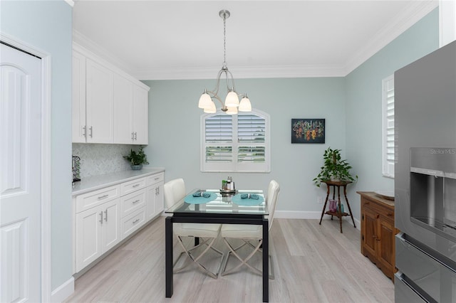 dining area with light hardwood / wood-style flooring, ornamental molding, and a chandelier