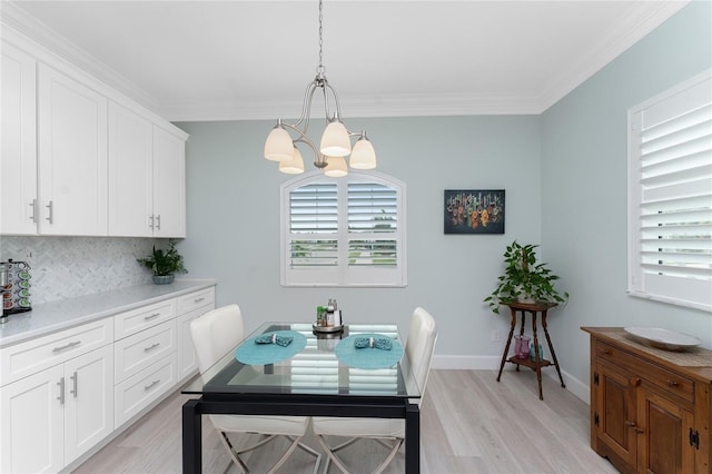 dining area with light hardwood / wood-style floors, crown molding, and an inviting chandelier