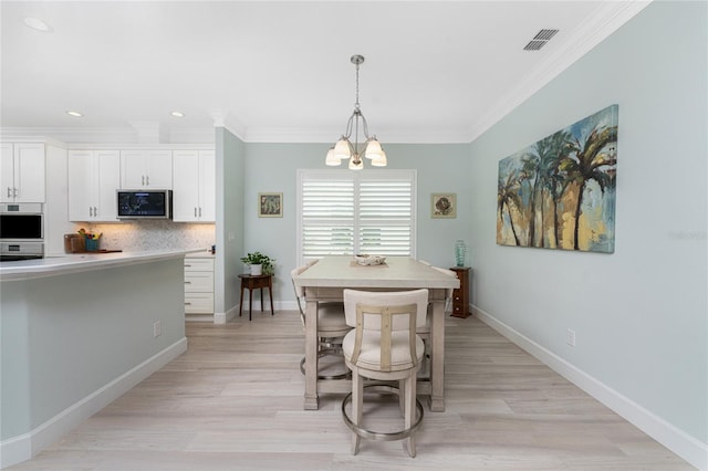 dining room with ornamental molding, an inviting chandelier, and light wood-type flooring