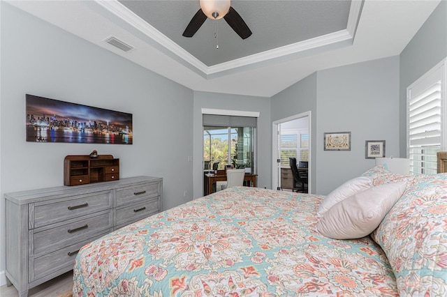 bedroom featuring light hardwood / wood-style floors, ornamental molding, a tray ceiling, and ceiling fan