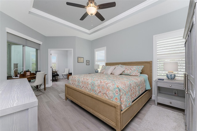 bedroom with crown molding, a tray ceiling, light wood-type flooring, and ceiling fan