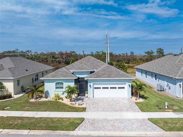 ranch-style house featuring a front lawn, decorative driveway, central AC, an attached garage, and a shingled roof