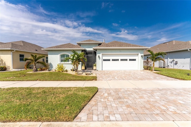 view of front of property with a front lawn, stucco siding, cooling unit, decorative driveway, and an attached garage