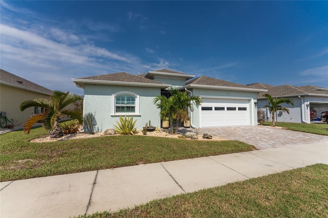 552 Box Elder Ct, Englewood, FL 34223 - view of front of house featuring stucco siding, an attached garage, decorative driveway, and a front lawn